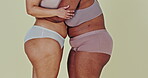 Body positivity, studio underwear and women hug to support shape, size and fashion acceptance inclusion. Closeup, friends and embrace with lingerie panties, bra and empowerment on green background