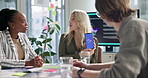 Woman, meeting and presentation for mobile app, software and show phone screen to team with ui. Business people, developer and ux designer group with smartphone, review and discussion at IT startup