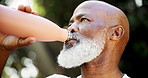 Senior black man, drinking water and outdoor for exercise, road and break for fitness, training or health in park. African person, bottle or hydration on street for detox, workout or thinking on path