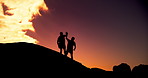 People, high five and fitness in sunset at beach with help on rocks, clouds and outdoor together. Men, support and lift for partnership, silhouette or goals in training, exercise or workout in summer