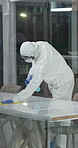 Man, hazmat suit and  wipe table for cleaning, pandemic and disinfection for virus safety. Person, spray bottle and lockdown for illness spread in office, sanitation or biohazard with policy or cloth