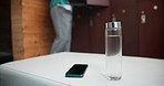 Health, man and back with water bottle and smartphone in gym dressing room for time and nutrition. Fitness, male person or athlete with glass container and mobile for connection and hydration