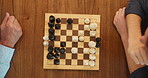 Chessboard, game and hands on desk, home or contest with strategy for problem solving with pawn. Board, toys and  above for people in challenge for king, knight and queen pieces with competition