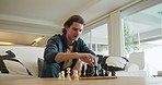 Man, chess and game in home on couch with strategy, solution or problem solving in contest in living room. Person, toys and board with competition for king, queen and knight with challenge in lounge