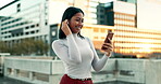 Woman, outdoor and happy on smartphone with earphones for music playlist and smile for entertainment. Female person, city and smile on internet for streaming service or social media and online video.