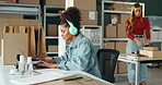 African woman, laptop and logistics with headphones, typing and reading by boxes, shelf or supply chain at startup. Person, employee and computer for music, storage and invoice admin for shipping job