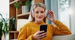 Happy woman, relax and headphones with phone for music, podcast or listening to sound on sofa at home. Female person with smile, headset or mobile smartphone for audio, playlist or album at house