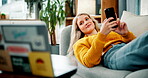 Girl, phone and laptop with relax on sofa for watching movie, streaming service or social media scroll in home. Woman, person and smartphone or tech for online series or lying down with entertainment