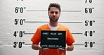 Man, criminal and arrest with sign for mugshot, violation or investigation for prison questioning. Portrait of male person or thief with orange clothing, billboard or number for jail photo or picture