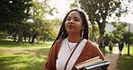 Black woman, student and walking with textbooks in nature for learning, education or studying at outdoor park. Young African with smile or books for academic journey or ambition at campus or college