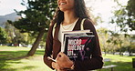 Happy woman, student and walking with science books in nature for learning, education or studying at outdoor park. Young female person with smile or microbiology textbooks for reading or research