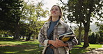 Happy woman, student and walking with books in nature for learning, education or path to university. Female person in stroll with textbooks at outdoor forest, campus or college for academic journey