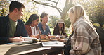 Students, laptop and conversation in park for study break with books and learn for english assessment or test. Computer, gen z people and friends talking outdoor for college education and knowledge