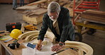 Carpenter, design and pencil with blueprint for construction, furniture or project. Senior handyman, drawing and wood with tools in a creative carpentry workshop for manufacturing, art and craft