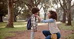 Black mother, child and forest with backpack for safety, love or care on path to school in nature. African mom helping little boy or kid getting ready with bag at outdoor park for learning journey