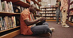 Student, african man or book on floor in library for reading, literature research or studying for knowledge. Gen z, novel or search for academic information for scholarship or education with learning