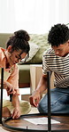 Moving, screwdriver and couple with table in new home for renovation, bonding and furniture building. Manual, paper and young man and woman assemble desk with instructions in living room at apartment