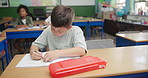 School, drawing and boy child in classroom at desk for education, learning or knowledge. Information, lesson and young kid with notebook for assessment, academic development or problem solving