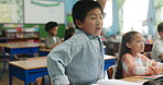 School, student and boy with answer, desk and learning in class, excited and question for studying. Education, child and raise of hand, growth and development in elementary, youth and notebook