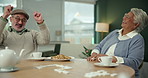 Senior man, woman and dominoes in home with fist pump, cheers and winning with strategy in retirement. Elderly couple, game and celebration with tea, cookies and relax together for success with food