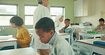 Teacher, desk and students in classroom for exam, test and knowledge in elementary school. Education, childhood development and paper for assessment, campus and learning for young people in academy 