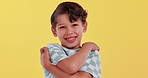 Self love, hug and face of child in studio for embrace, affection and loving on yellow background. Happy, excited and portrait of young boy smile with confidence, pride and pleasure for comfort
