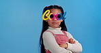 Fashion, sunglasses and face of girl in studio for confidence, trendy style and cool accessories. Happy, smile and portrait of young child with eyewear for joy, pride and cute on blue background