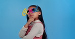 Fashion, sunglasses and child in studio thinking for confidence, trendy style and cool accessories. Funky, smile and portrait of young girl with eyewear for ideas, pride and cute on blue background