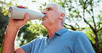 Senior man, drinking water and walk in park for health, wellness and detox to start morning in summer. Person, bottle and hydration for exercise, fitness and outdoor with sunshine in New Zealand