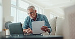 Senior man, tablet and laptop with documents on sofa for investment, insurance or application at home. Elderly male person with paperwork on technology for trading, investing or payments at house