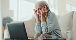 Laptop, headache and senior woman on sofa with stress for debt, mistake or mental health crisis at home. Pc, frustrated or old person in living room confused by how to, subscription or sign up doubt 