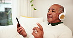 Home, relax and old man with headphones, smartphone and break with radio, listening to music and social media. Pensioner, apartment and senior guy on couch, headset and cellphone with audio and song