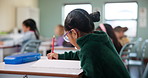 Child, student and writing in classroom for learning, education and problem solving by desk with knowledge. Girl, study and exam in elementary school with pencil for development, growth and project