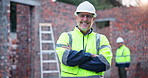 Smile, crossed arms and face of man construction worker on site for building and renovation management. Happy, portrait and mature male contractor in civil engineering for repairs or maintenance.