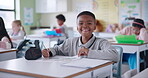 African boy, face and happy in classroom with creative learning, skills development or coloring for school activity at desk. Portrait of smart and confident student laughing and excited for education