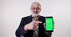 Senior man, pointing or phone for green screen, mockup space or app notification in studio on white background. Online ads, face or pensioner on mobile technology for deal, announcement and promo