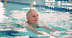 Senior woman, swimming and workout in pool for health with aquatic sports, retirement and physiotherapy. Elderly lady, water gym and rehabilitation for arthritis, hydrotherapy and cardio exercise