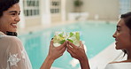 Women, cheers and drinks at hotel pool for holiday, happiness and relax with glass, alcohol and smile. Friends, celebrate and gin cocktail together at luxury resort for vacation, wellness and travel