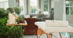Bed, table and equipment with interior at beauty spa for salon, relaxation or therapy treatment at outdoor resort. Empty retreat with incense, candles and natural organic products at holiday getaway