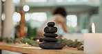 Woman, candle and stones with masseuse by bed for beauty spa, physical therapy or zen at luxury resort. Female person, beautician or therapist preparing table for service or hospitality at salon