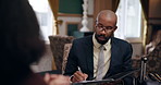 Black man, working and communication in hotel with paper for questions, speaking with employee for hospitality. Male recruiter, resort and conversation with staff for interview or recruitment hiring