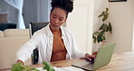 Black woman, home and remote work with laptop and paperwork for administration or data capture. Female person, employee and serious in desk at apartment with documents, typing report and information