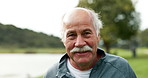 Smile, nature and face of senior man with confidence for retirement vacation with outdoor exploring. Happy, pride and elderly male person from Canada in outdoor park, garden or field with wind.