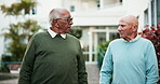 Elderly people, walking and talking in retirement home as friends, partner or community in conversation. Senior men, bonding and support in outdoor of nursing village with discussion, chat and unity