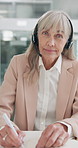 Senior woman, consultant and writing with headphones at call center for customer service or report at office. Portrait or pov of mature female person or agent taking notes with book for online help