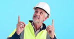 Pointing, man and construction worker in studio with mockup space for building option or decision. Hardhat, smile and mature industrial foreman with presentation gesture for choice by blue background