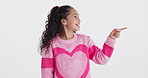 Pointing, happy and face of child in studio for promotion, bargain and discount news on white background. Excited, fashion and portrait of isolated young girl with hand gesture for announcement