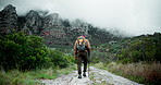 Mature man, hiker and walking with stick on mountain for fitness, adventure or outdoor journey in nature. Back view of male person trekking with backpack, bag and cloudy sky in natural environment