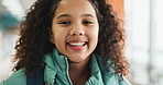 Girl, child and happy with face at school with backpack in corridor for education, knowledge and academy. Kid, portrait and bag in hallway for progress, learning and smile for future in Colombia