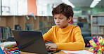 Boy, library and child on laptop for online class, remote education and e learning with knowledge. Virtual school, development and male student typing on technology for growth on teaching platform